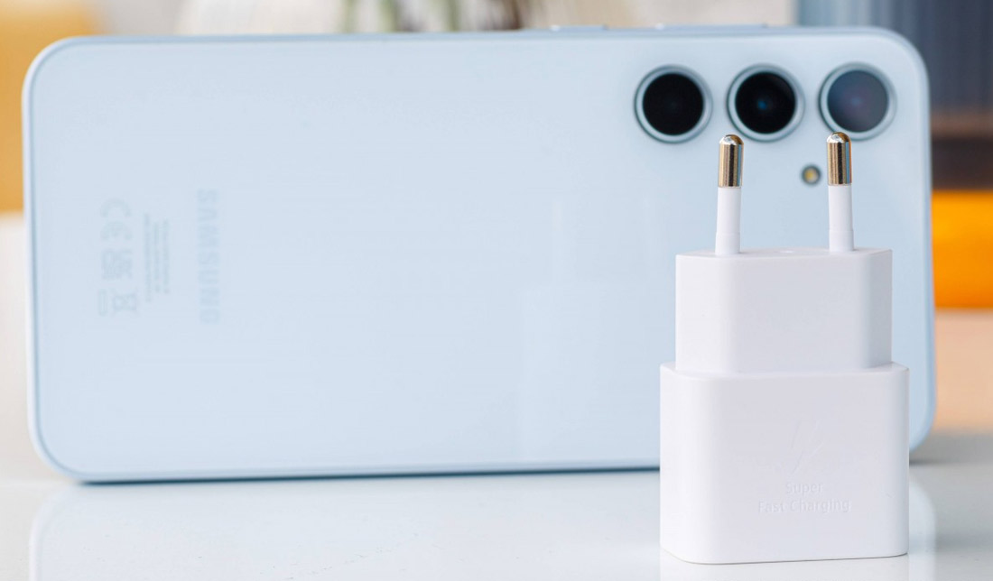 آداپتور شارژر گوشی ‏A35‎‏ به همراه خود گوشی در رنگ‌ سفید بر روی میز